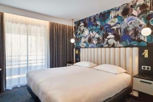 波亚克Best Western Premier Hotel des Vignes et des Anges的卧室配有一张大床,墙上挂有绘画作品