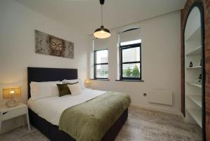 利兹Stylish & Elegant city centre apartment的一间卧室设有一张大床和两个窗户。