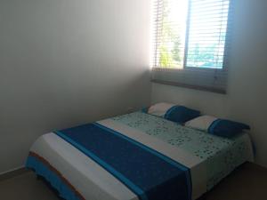 科韦尼亚斯Cómodo apartamento cerca al mar的一间卧室配有一张带蓝色床单的床和一扇窗户。