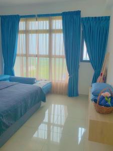 马六甲Atlantis Residence Melaka ForMuslims Homestay的一间卧室配有蓝色窗帘和大窗户