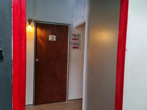 雪邦Ayden Hostel Airport Transit - KLIA的一间设有棕色门和红色窗帘的房间