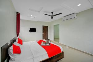 KurmannapalemOYO VRK Residency的卧室配有红色和白色的床和吊扇