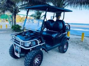圣佩德罗Coastal Bay Suite & Golf Cart Rental的海滩上停放的黑色高尔夫球车