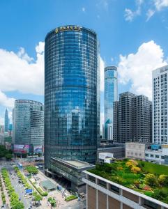 深圳深圳华强广场酒店 - 住客尊享免费欢乐下午茶&迷你吧&宵夜 的一座高大的玻璃建筑,在城市里