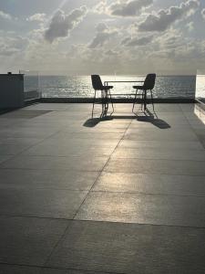 纳哈里亚מלון בוטיק H34的两把椅子和一张桌子坐在海边的木板路上