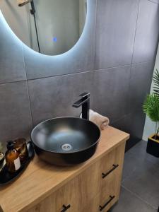 IpoteştiLa Cetate Luxury Apartment的浴室设有木制梳妆台上的黑色盥洗盆。