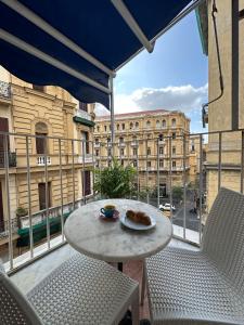 那不勒斯B&B Quattro Palazzi Napoli Centro的阳台享有建筑景致,配有桌椅。