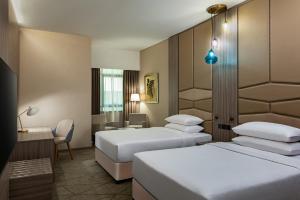 迪拜Four Points by Sheraton Production City, Dubai的酒店客房,配有两张床和椅子