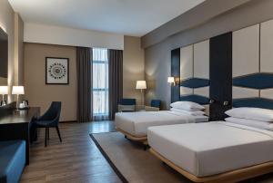 迪拜Four Points by Sheraton Production City, Dubai的酒店客房配有两张床和一张书桌