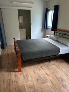 Dundee BeachAnchors down accommodation的一间卧室设有一张大床,铺有木地板