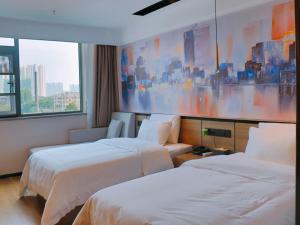 阜阳格菲阜阳市火车站北京东路酒店的酒店客房设有两张床,墙上挂有绘画作品