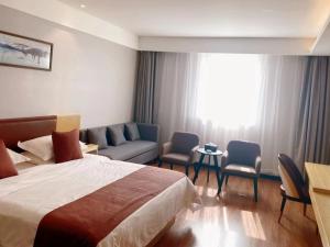 Taozhuang格丽枣庄高铁站酒店的酒店客房配有床、椅子和沙发。
