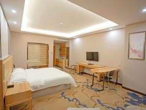 宜春格菲宜春市袁州区政府高铁站酒店的一间卧室配有一张床、一张书桌和一台电视