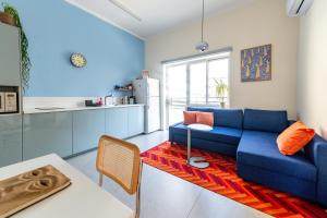 特拉维夫My TLV City suite的一间带蓝色沙发的客厅和一间厨房