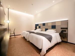 南宁格丽酒店南宁火车东站店的卧室配有一张白色大床和一张书桌