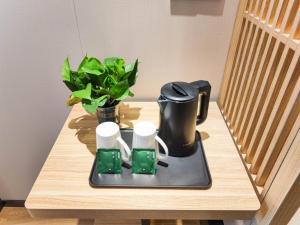 Hejialiang格林豪泰兰州中川机场兰石酒店的茶壶桌子和茶壶上的植物