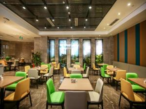 重庆格林东方重庆解放碑儿童医院酒店的餐厅设有桌子和绿色椅子以及窗户。