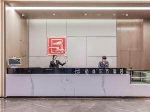 重庆格林东方重庆江北国际机场鹿山地铁站酒店的两个人站在大厅的柜台上