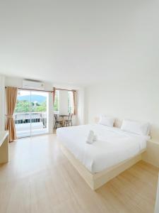 拉廊Tanatnan Hotel的白色卧室设有一张大床和一个阳台