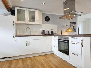 兰河畔马尔堡Tucan - Rooftop Terrace with View, BBQ, PS4+Stream的厨房配有白色橱柜、水槽和炉灶。