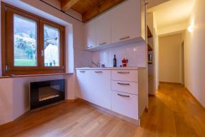 PugernaCasa Gialla - Happy Rentals的厨房配有白色橱柜和壁炉