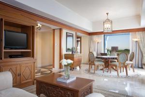 日惹凯悦日惹酒店的客厅配有桌椅和电视。