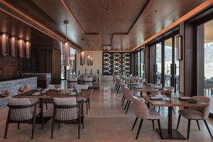 欧拉Banyan Tree AlUla的餐厅设有木桌、椅子和窗户。
