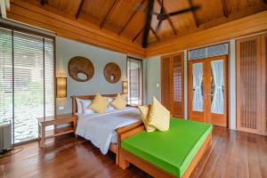彭世洛帕坦拉Spa度假酒店的一间卧室配有一张床和一个绿色长凳