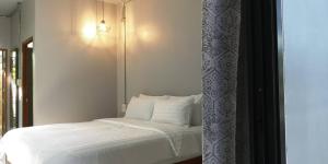 素叻司隶素叻他尼旅馆的一张带白色床单和枕头的床