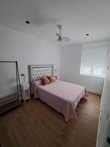 哈恩Piso Jaén Parque的一间卧室配有一张带粉色床单的床和风扇