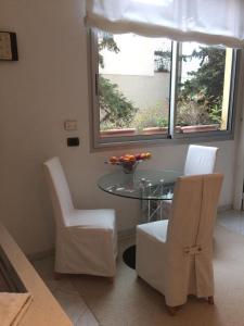 艾日Appartamento "Renata" in residence Cap Roux Eze Borde de Mer Costa Azzurra的一间设有玻璃桌和白色椅子的用餐室