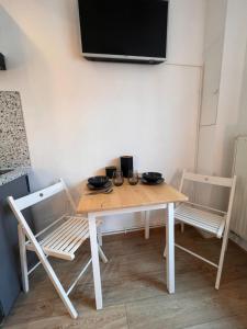 科洛米耶Studio « Le petit Prat »的一张桌子、两把椅子和墙上的电视