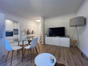 巴塞尔Stylish 1-bedroom condo close to exhibition square的客厅配有桌椅和电视。