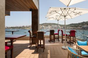 圣保罗湾城Ushuaia Playa Xemxija Boutique Hotel的一间带桌椅并享有水景的餐厅