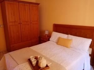 Valles de OrtegaCasa Palmés的一间卧室配有一张床,并备有一个装有杯子的托盘