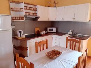 Valles de OrtegaCasa Palmés的厨房配有白色橱柜和一张带篮子的桌子