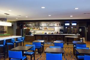 麦迪逊Courtyard by Marriott Madison East的一间设有蓝色桌椅的餐厅和一间酒吧