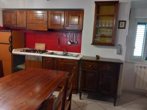 卡普拉科塔LA CASA IN PIAZZA的厨房配有木制橱柜和木桌。
