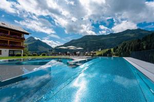 达米尔斯Hotel Alpenblume的一座大游泳池,后面是群山