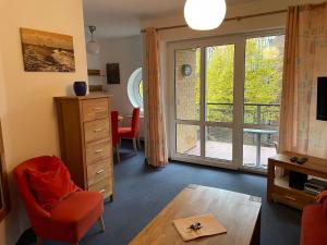 科瑟罗Seeblick Wohnung 115的客厅配有红色椅子和滑动玻璃门