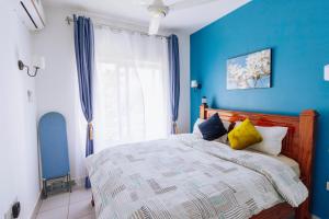 FumbaFumbatown Cozy 1 bed Apartment的一间卧室拥有蓝色的墙壁,配有一张带黄色枕头的床。
