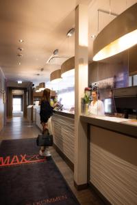 萨尔茨堡Hotel Das Junior by MAX 70的站在餐厅柜台的女人