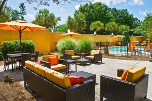 查尔斯顿Courtyard by Marriott North Charleston Airport Coliseum的庭院配有桌椅和遮阳伞。
