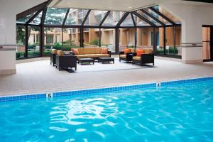 阿灵顿海茨芝加哥南阿灵顿海兹万怡酒店的一座带沙发和椅子的游泳池,毗邻一座建筑