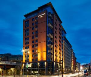 格拉斯哥Leonardo Royal Hotel Glasgow的夜幕降临的城市街道上一座高楼
