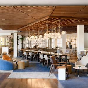 洛杉矶Hilton Los Angeles-Culver City, CA的餐厅设有木制天花板和桌椅