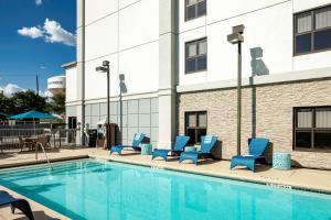 圆石城Hampton Inn Austin Round Rock的一座带蓝色躺椅的游泳池,位于大楼旁