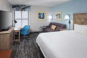 圆石城Hampton Inn Austin Round Rock的酒店客房配有一张床、一张桌子和一把椅子。