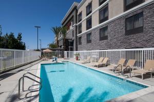 赛普里斯Hampton Inn Los Angeles Orange County Cypress的一座带椅子的游泳池以及一座建筑