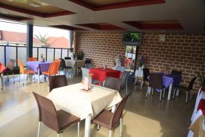 姆巴拉拉Jatheo Hotel Rwentondo的一间带桌椅的餐厅以及砖墙